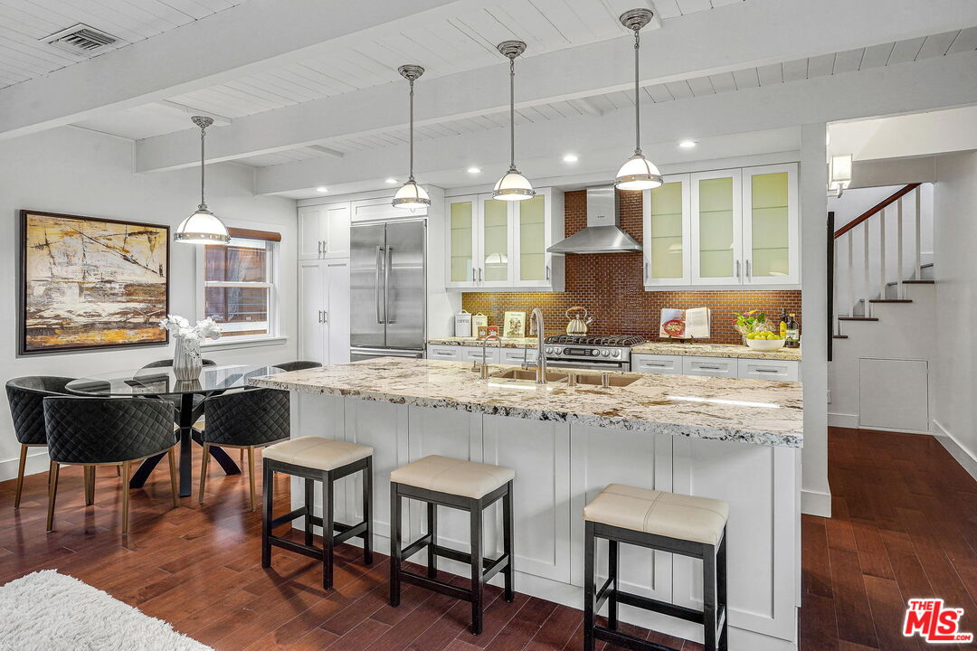 a kitchen with granite countertop a stove a sink a dining table and chairs with wooden floor