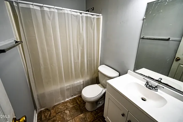 a bathroom with a sink a toilet a mirror and shower curtain