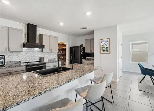 a kitchen with stainless steel appliances granite countertop a stove top oven a sink a dining table and chairs
