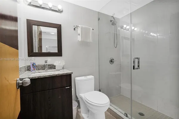 a bathroom with a granite countertop sink toilet a mirror a vanity and shower