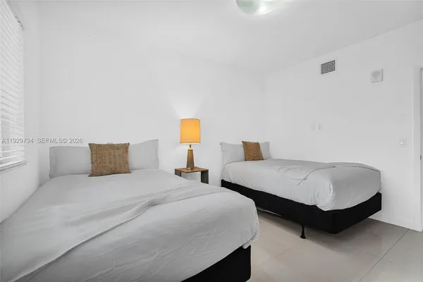 a bedroom with two beds and a lamp