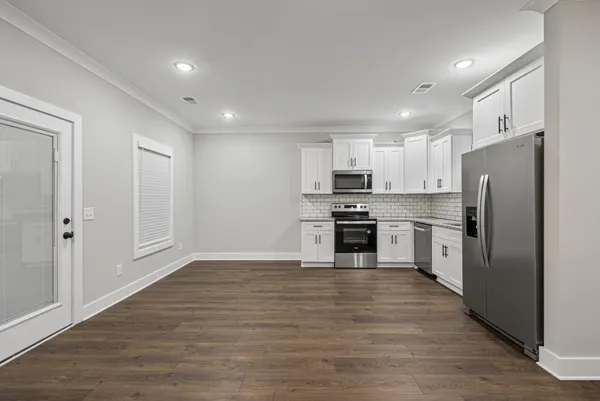 a kitchen with a refrigerator a sink and white cabinets