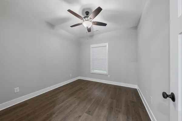 an empty room with wooden floor and ceiling fan