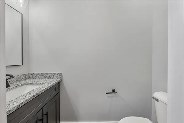 a bathroom with a granite countertop sink and a toilet