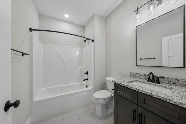 a bathroom with a granite countertop sink a toilet and shower