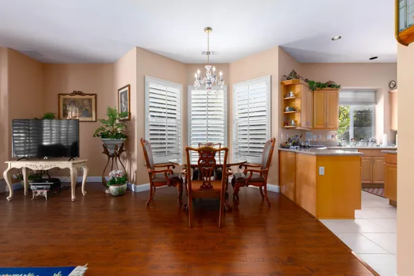 a dining room with wooden floor a chandelier a glass table and chairs