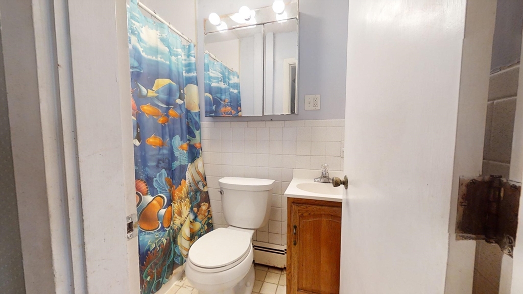 57 Church Street Watertown, MA 02472 - Photo 10 of 18 a white toilet sitting next to a bathroom sink and a mirror