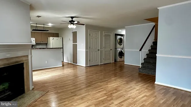 a view of a kitchen and an empty room with wooden floor