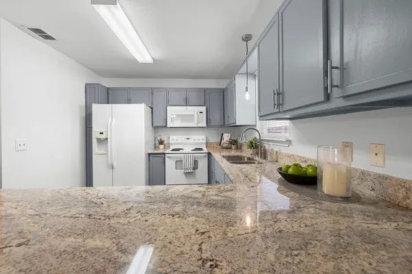 a kitchen with stainless steel appliances granite countertop a refrigerator a stove a sink and white cabinets