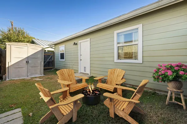 a backyard of a house with wooden table and chairs