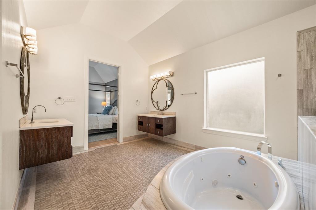 1521 Newton Ranch Road Keller, TX 76248 - Photo 21 of 40 Soaking tub with deck-mounted faucet, dual floating vanities with countertop sinks, and wall-mounted light fixtures