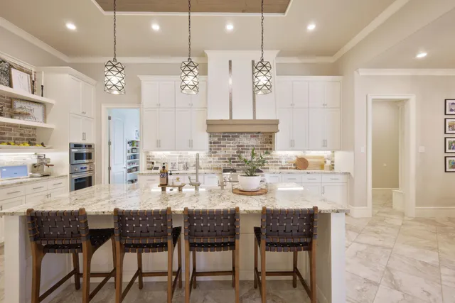 a kitchen with kitchen island granite countertop a dining table chairs sink and cabinets
