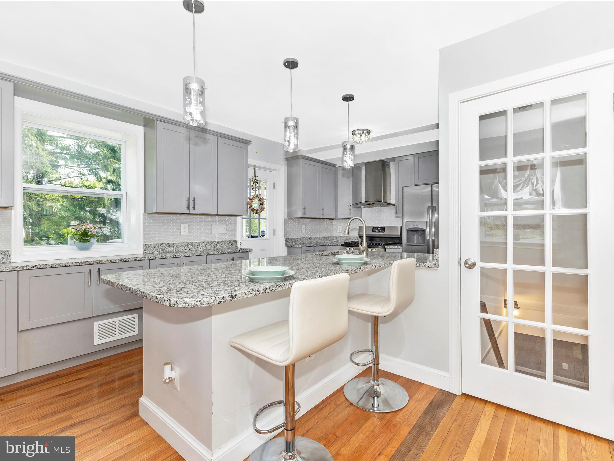 507 Kerwin Court Silver Spring, MD 20901 - Photo 15 of 51 a kitchen with kitchen island granite countertop a table chairs and a wooden floor