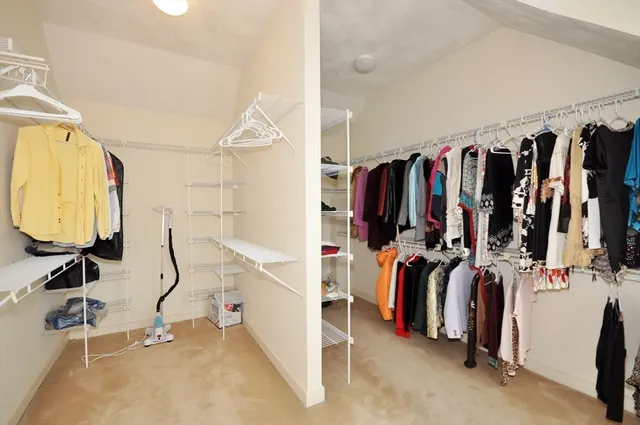 a view of walk in closet with clothes and shoes