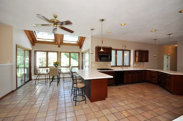 a kitchen with stainless steel appliances granite countertop a stove a sink a dining table and chairs with wooden floor