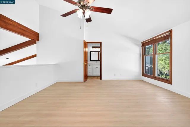 an empty room with windows and fan