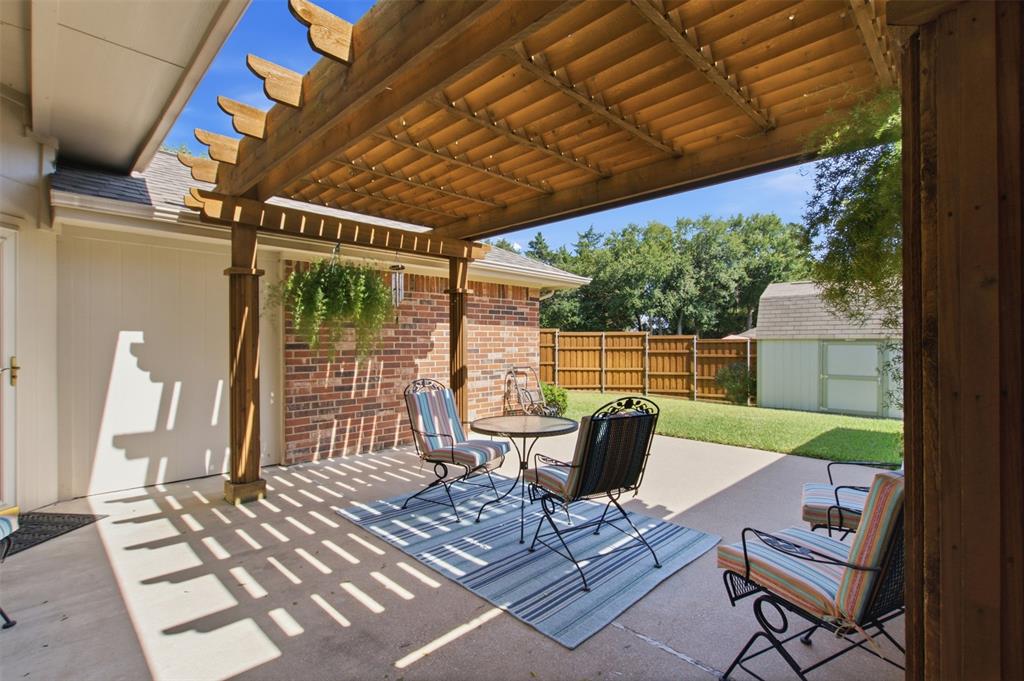 4218 Glistening Spring Rowlett, TX 75088 - Photo 33 of 39 Expansive concrete patio featuring a wood pergola, brick exterior wall, and a fenced backyard with a detached shed