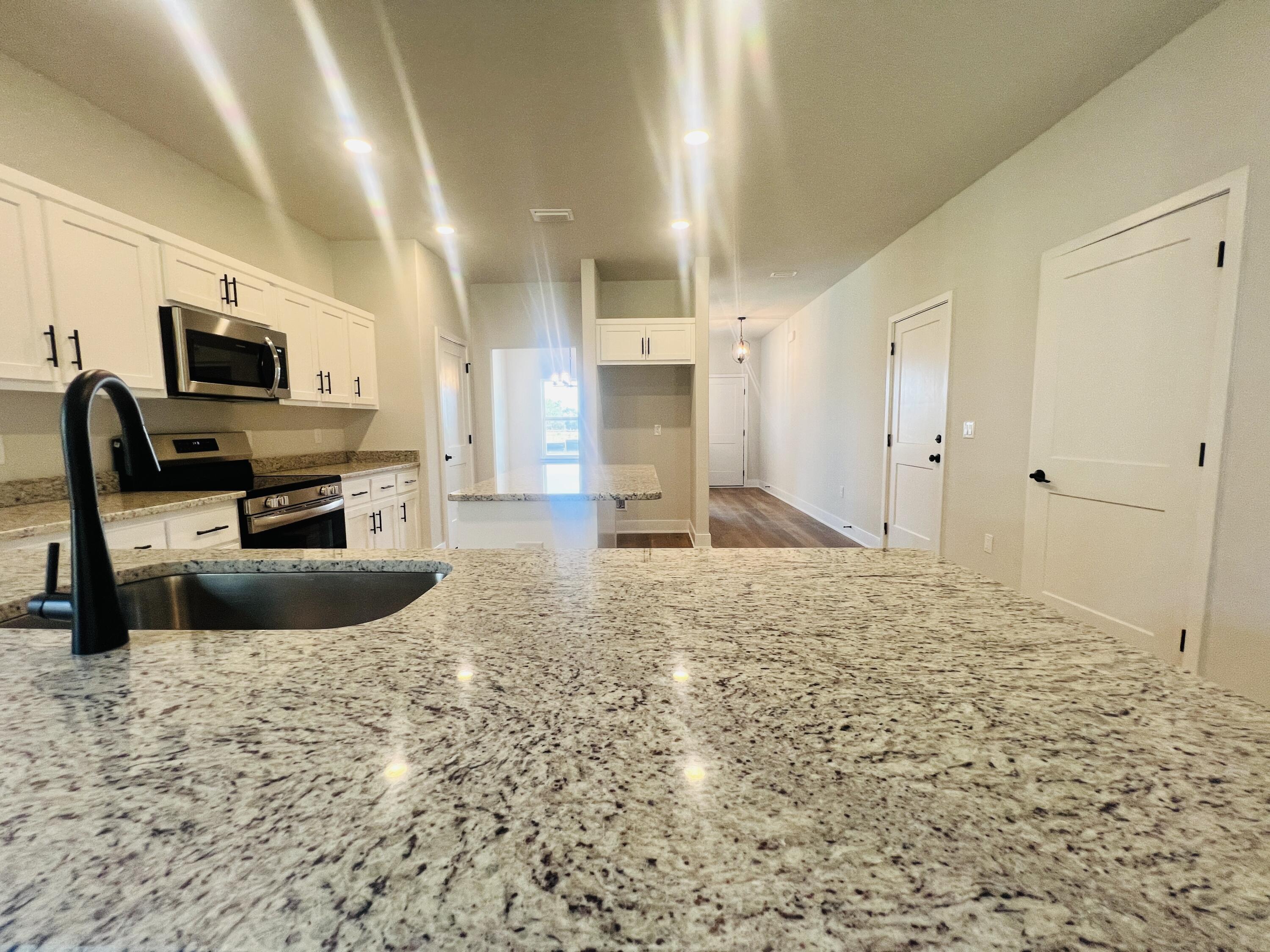 5299 Hidden Pines Circle Milton, FL 32583 - Photo 12 of 33 a large kitchen with granite countertop a sink a counter top space appliances and cabinets
