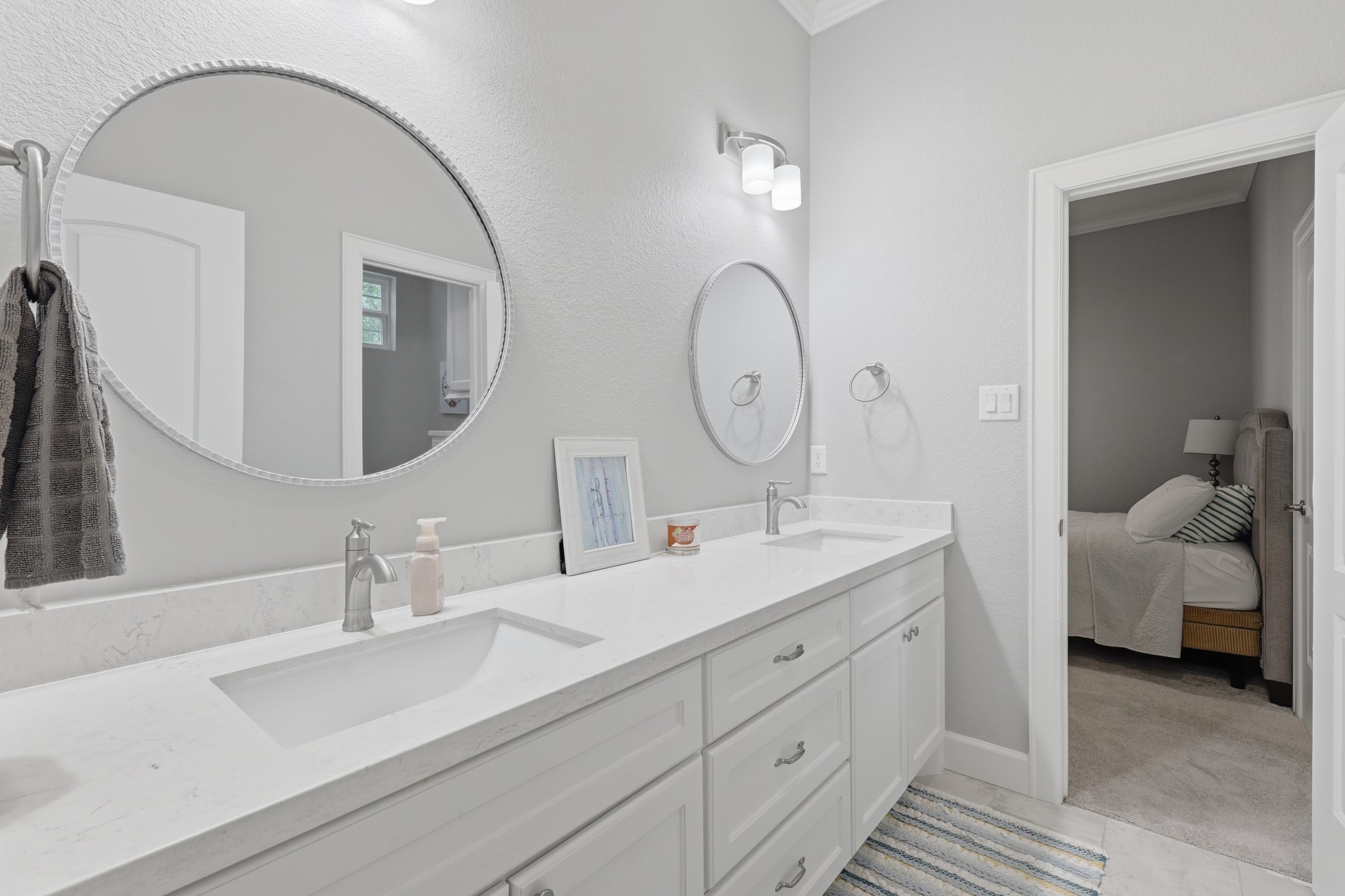 7106 Hampton Court Spring, TX 77389 - Photo 15 of 31 Modern guest bathroom with a dual-sink vanity, white cabinetry, and round mirrors. The space is bright and elegant, with a neutral color scheme.