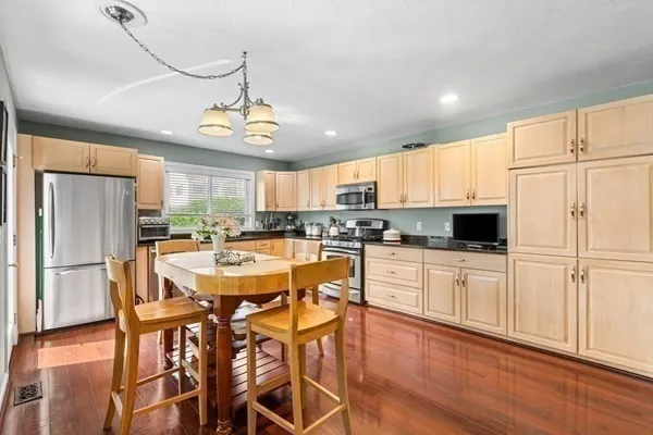 a kitchen with stainless steel appliances granite countertop a refrigerator a stove top oven a sink dishwasher and white cabinets with wooden floor