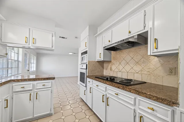 a kitchen with white cabinets and appliances