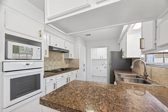 a kitchen with granite countertop a stove sink and refrigerator