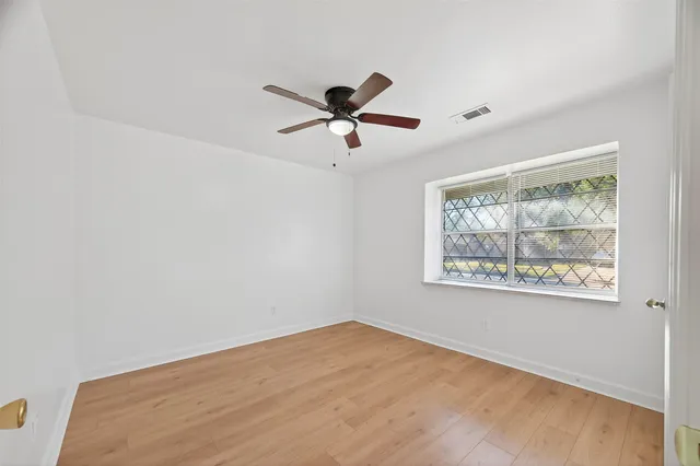 a view of empty room with wooden floor and ceiling fan