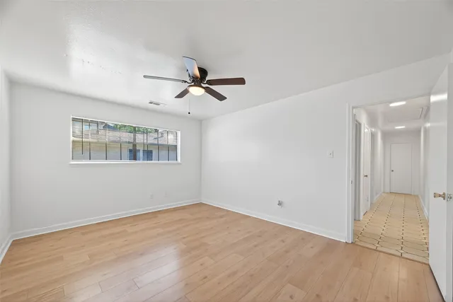an empty room with wooden floor and ceiling fan