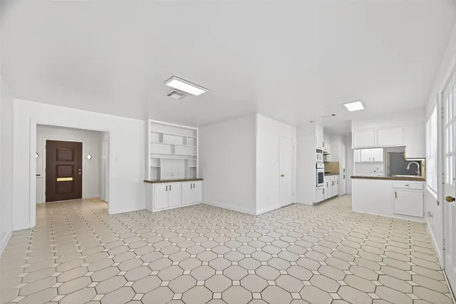 a living room with stainless steel appliances kitchen island granite countertop a refrigerator and white cabinets