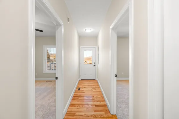 a view of a hallway with wooden floor and a bathroom
