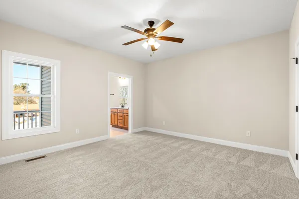 an empty room with ceiling fan and window