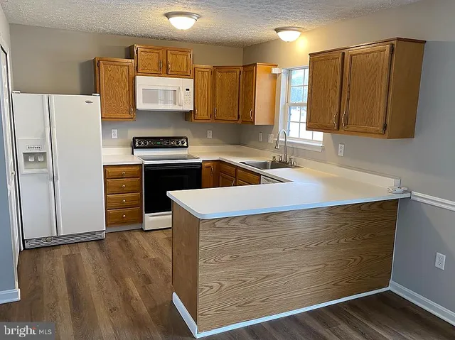 a kitchen with granite countertop a sink a stove and refrigerator