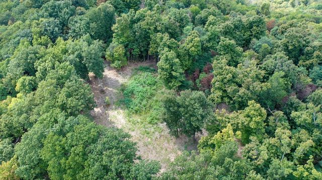 an aerial view of residential house with outdoor space and trees all around
