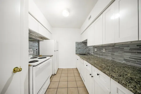 a kitchen with granite countertop a sink stove and cabinets