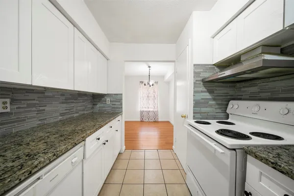 a kitchen with granite countertop a sink a stove and cabinets