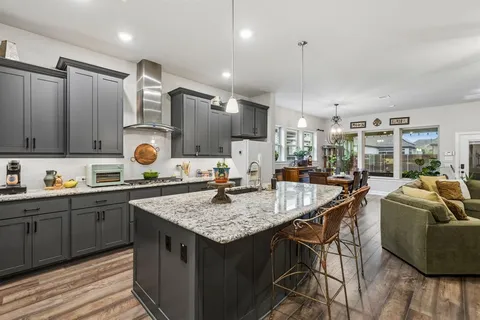a kitchen with stainless steel appliances granite countertop a sink a stove and a wooden floors