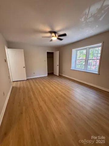 an empty room with windows and ceiling fan