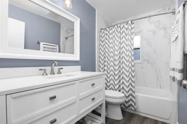 a bathroom with a granite countertop sink toilet a mirror a bathtub and shower