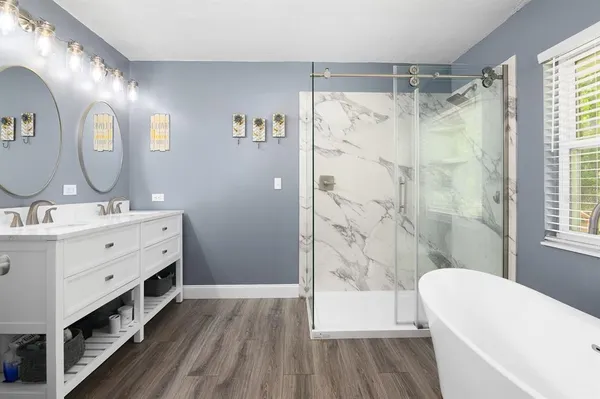 a bathroom with a double vanity sink a mirror a shower and a bathtub