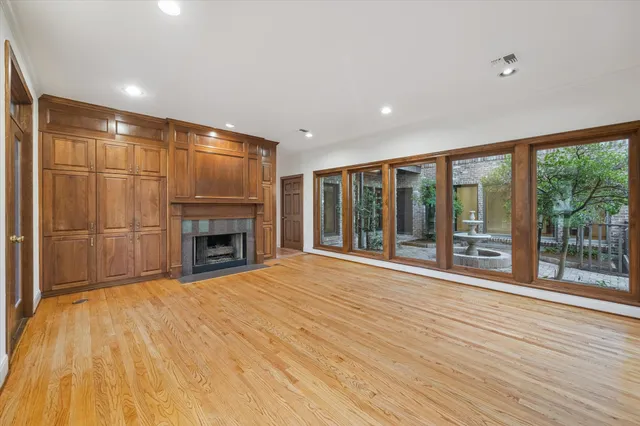 a view of an empty room with wooden floor and a fireplace
