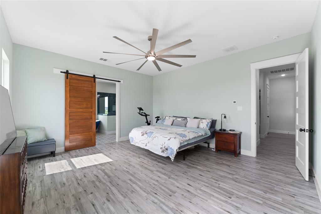 4411 Fm 751 Wills Point Wills Point, TX 75169 - Photo 20 of 40 Spacious room featuring wood-finish flooring, a contemporary ceiling fan, and a barn door leading to an adjoining area