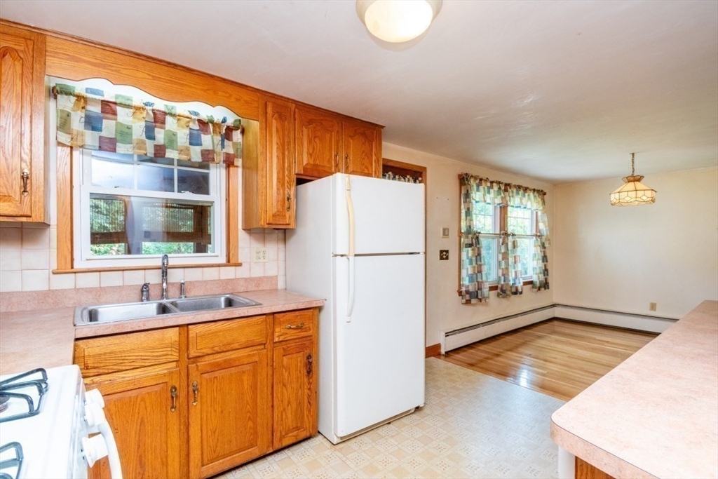 5 Edward Street Canton, MA 02021 - Photo 8 of 24 a kitchen with stainless steel appliances granite countertop a refrigerator a sink and white cabinets with wooden floor