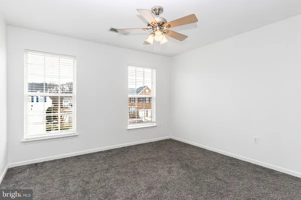 an empty room with windows and ceiling fan