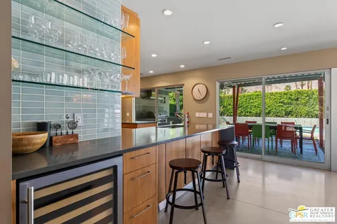 a dining hall with stainless steel appliances granite countertop a table chairs and a living room view