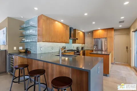 a kitchen with stainless steel appliances granite countertop a sink a stove a refrigerator cabinets and chairs