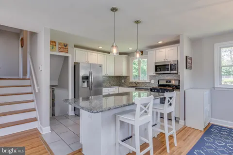 a kitchen with stainless steel appliances granite countertop a refrigerator a stove a microwave oven a sink with island and chairs