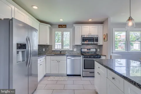 a kitchen with stainless steel appliances granite countertop a refrigerator and a stove top oven