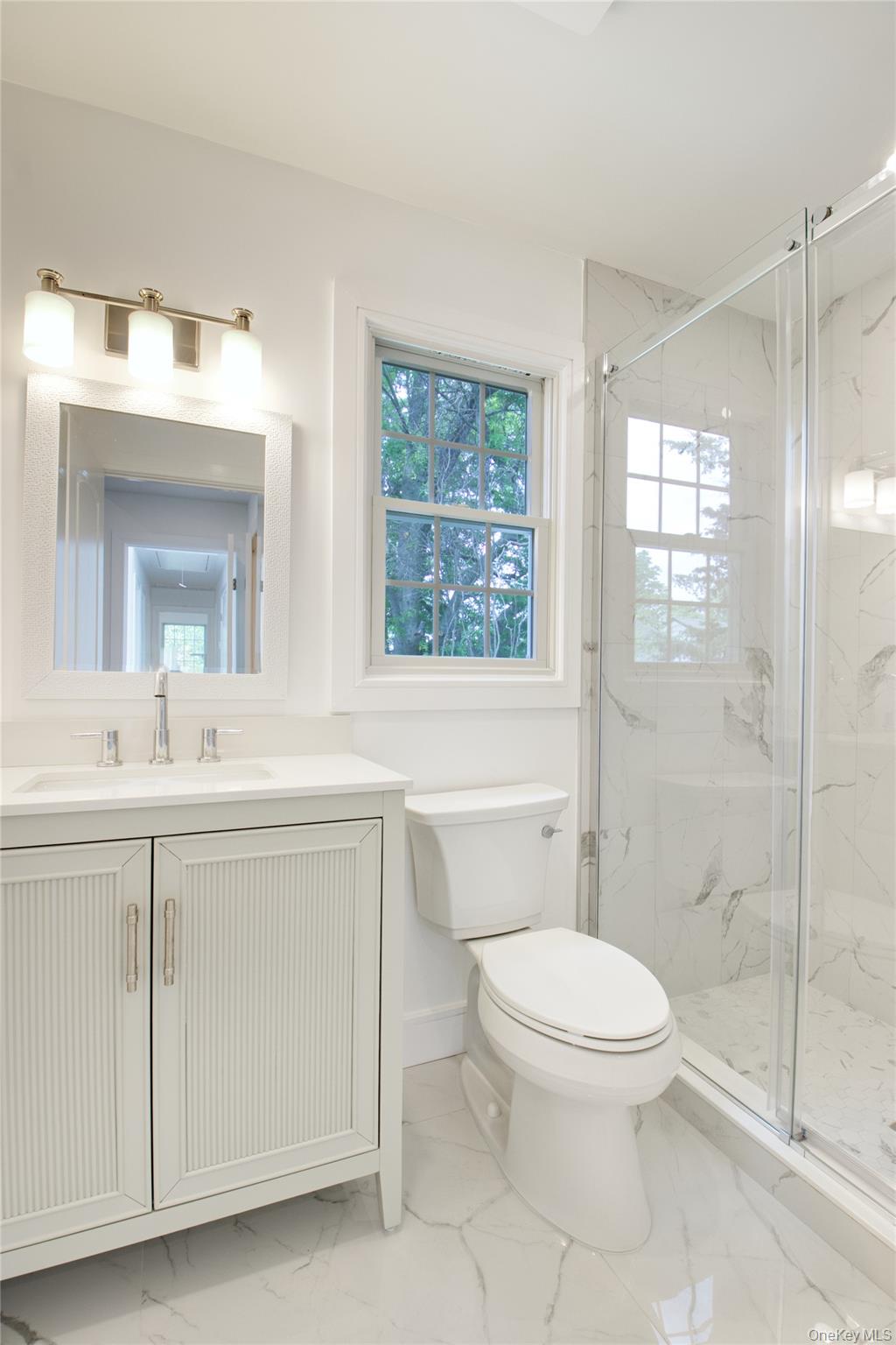 30 Kirkwood Road, Unit B Port Washington, NY 11050 - Photo 18 of 36 a bathroom with a toilet a sink a mirror a window and vanity