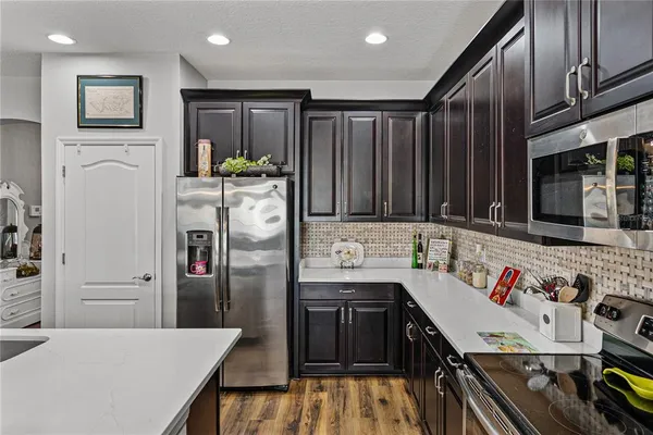 a living room with furniture kitchen view and a wooden floor