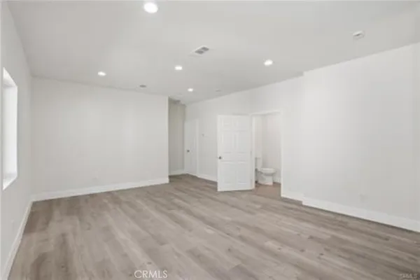 a view of a hallway with wooden floor and a bathroom